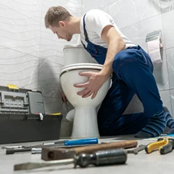 man plumber in uniform installing toilet bowl using instrument kit professional repair service